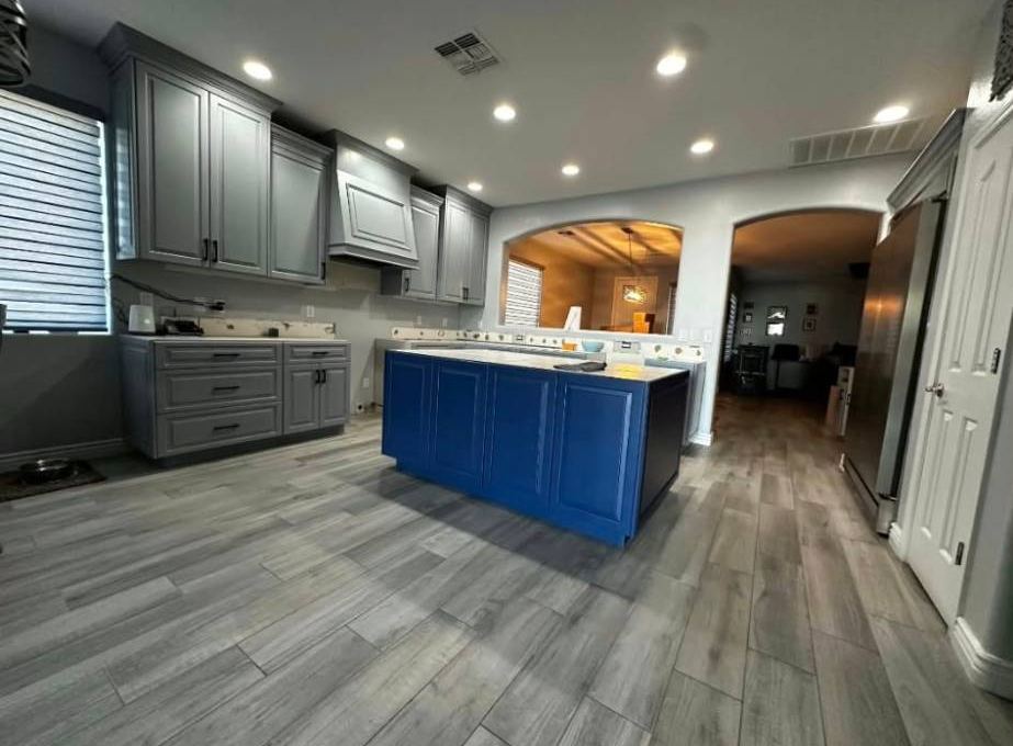 Gray raised-panel kitchen cabinets with a blue island