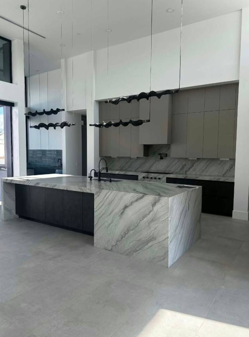 Kitchen with a waterfall stone island and flat-panel cabinets