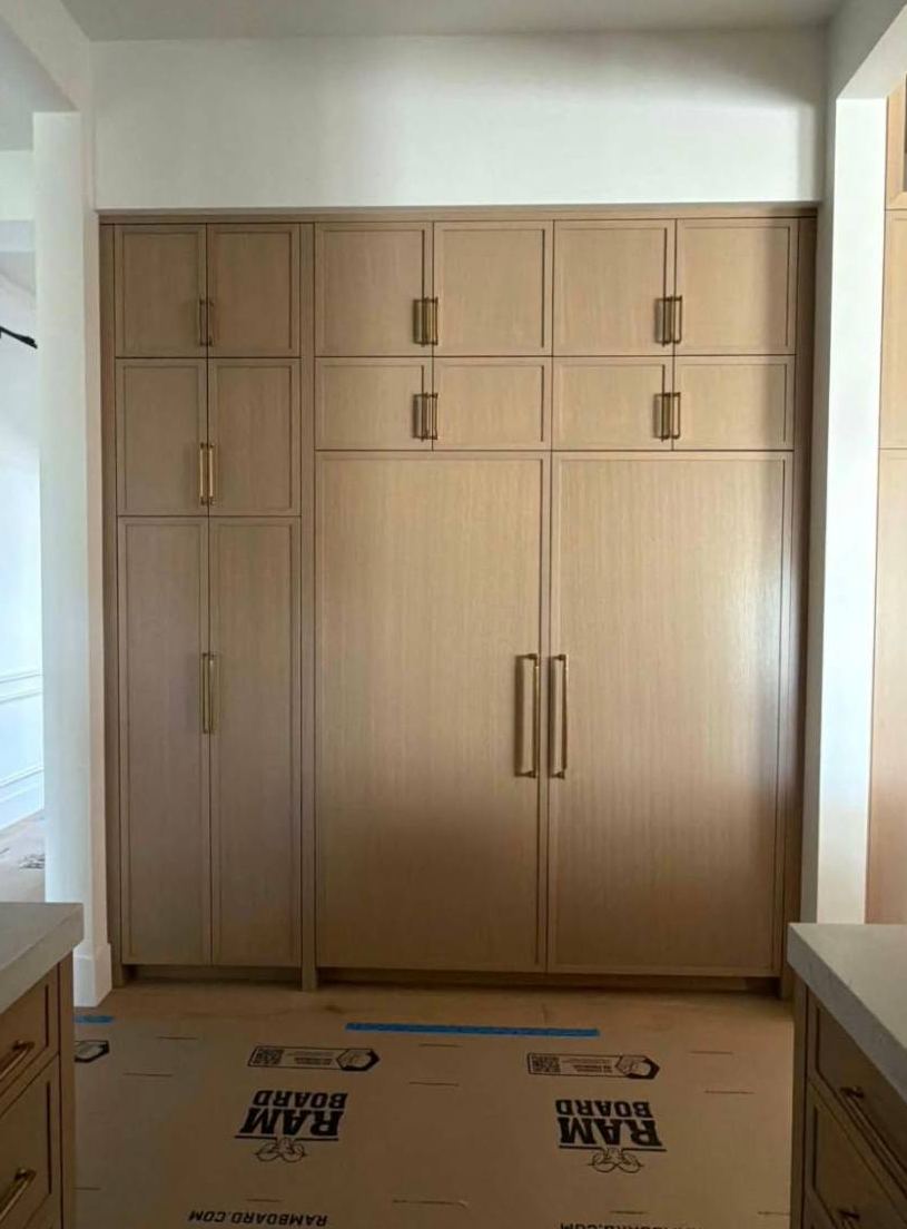 Floor-to-ceiling oak pantry cabinets with brass pulls